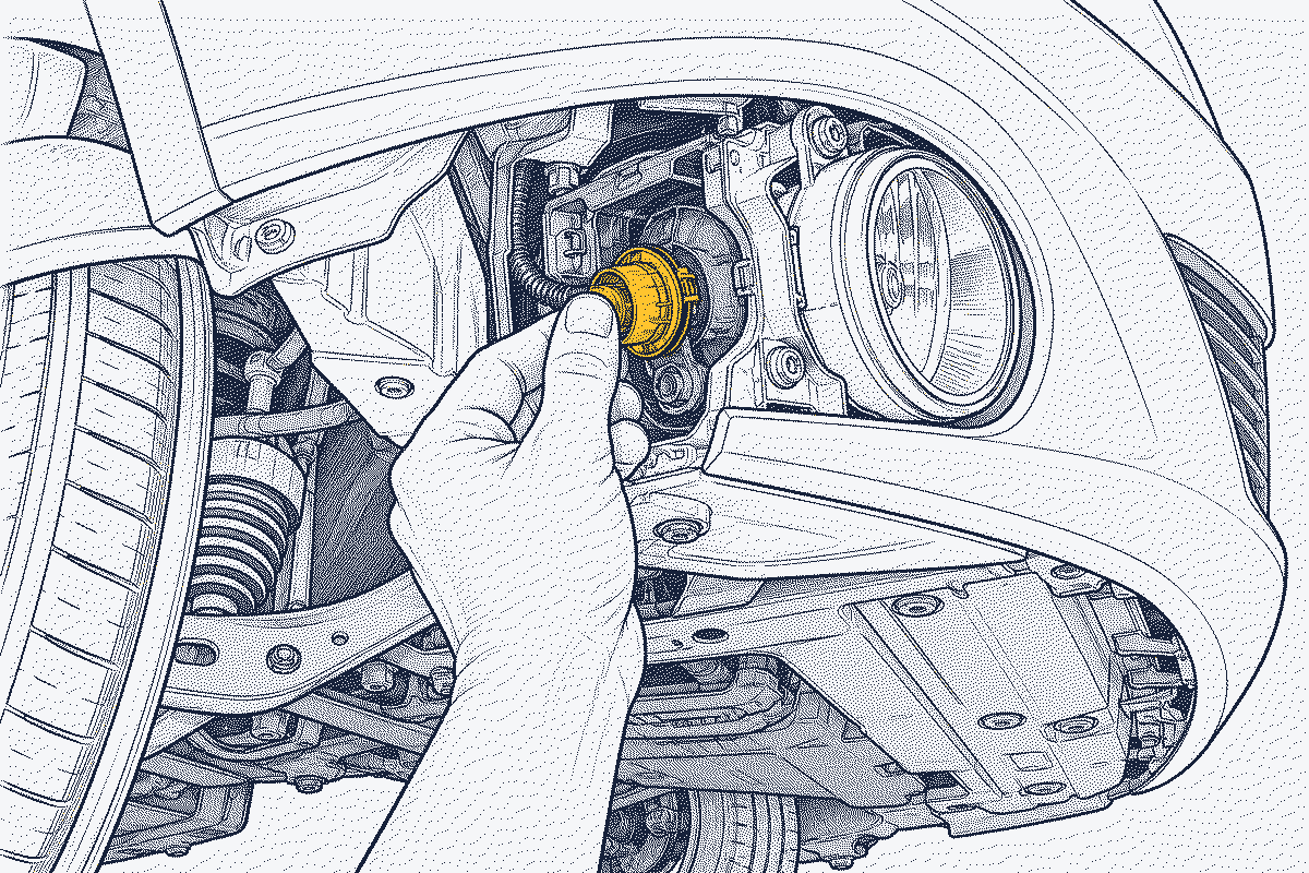Hand reaching behind a front bumper to twist a fog lamp bulb out of its housing