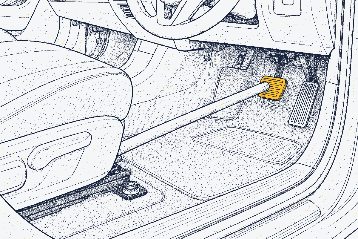 Driver's footwell with a long wooden pole wedged between the brake pedal and the front edge of the seat