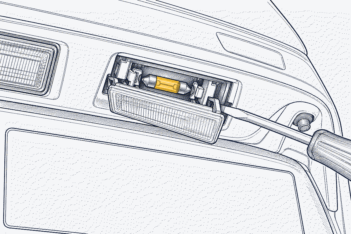 Underside of a car's rear number plate lamp with the lens unclipped and a festoon bulb exposed
