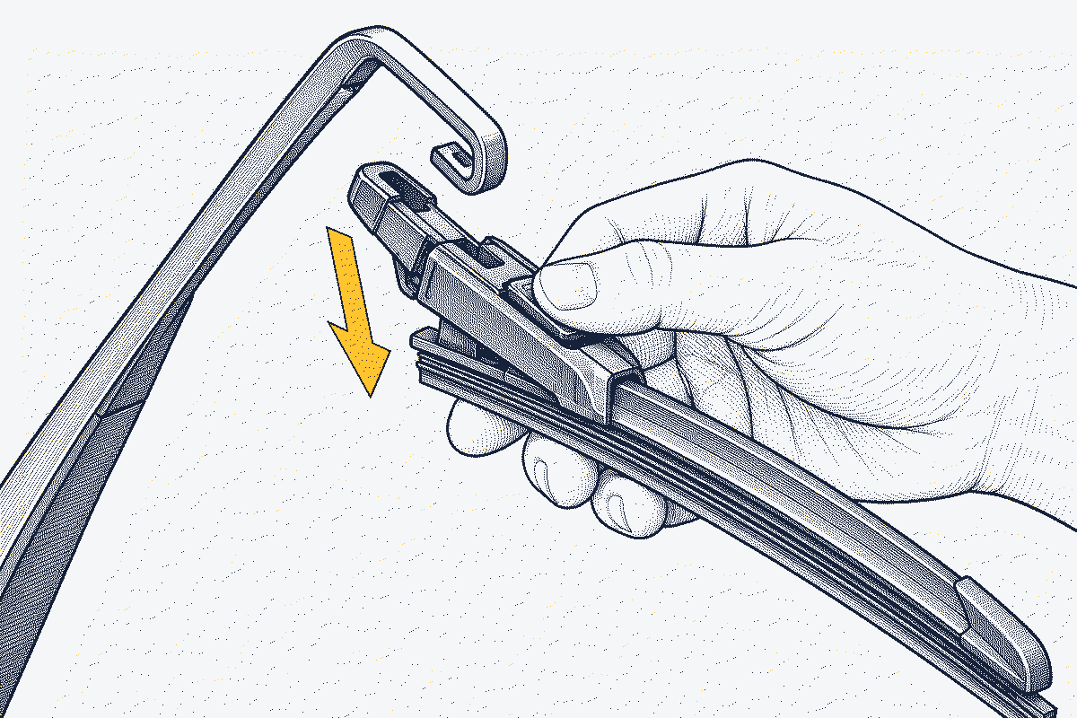 Hand pressing the release tab on a wiper blade adapter and sliding the blade down out of a U-hook arm